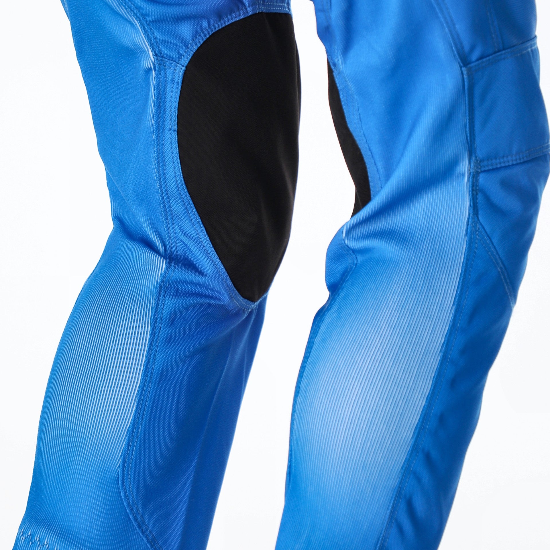 Close-up of blue motocross pants with black knee protectors, shown on a white background.