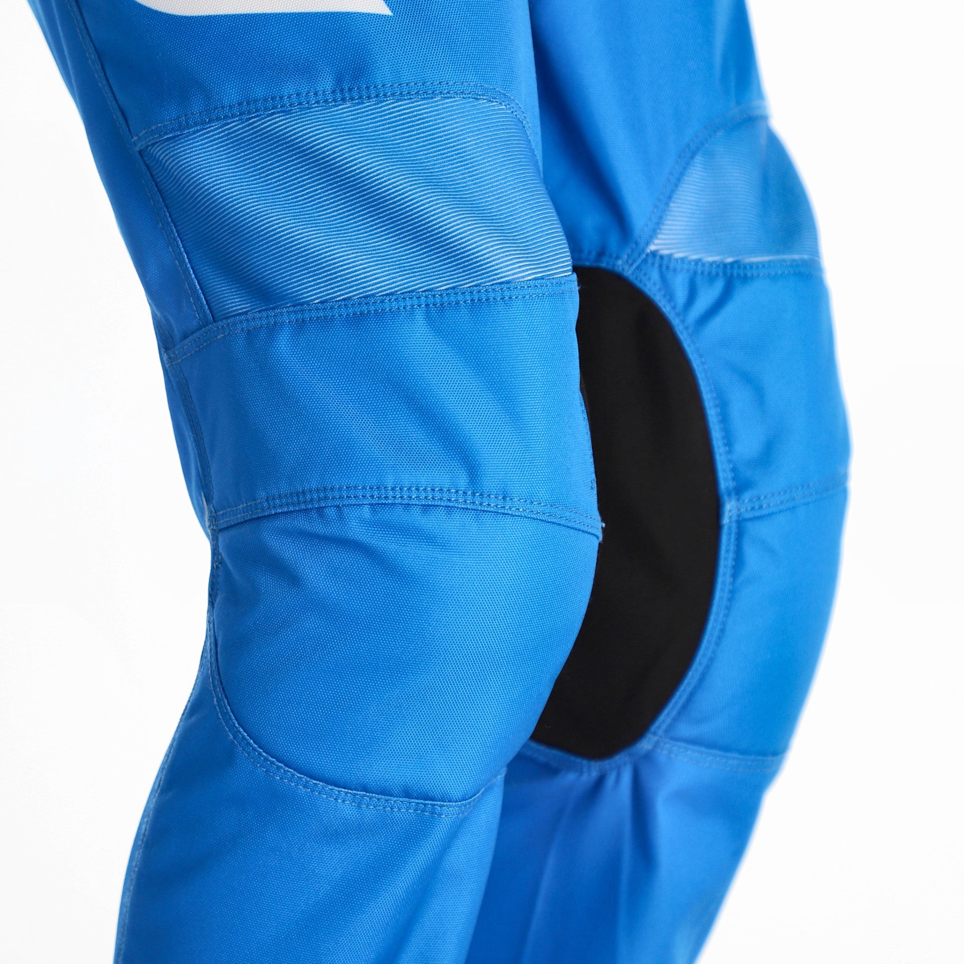 Close-up of bright blue protective athletic pants with segmented paneling and a black knee insert, shown on a white background.