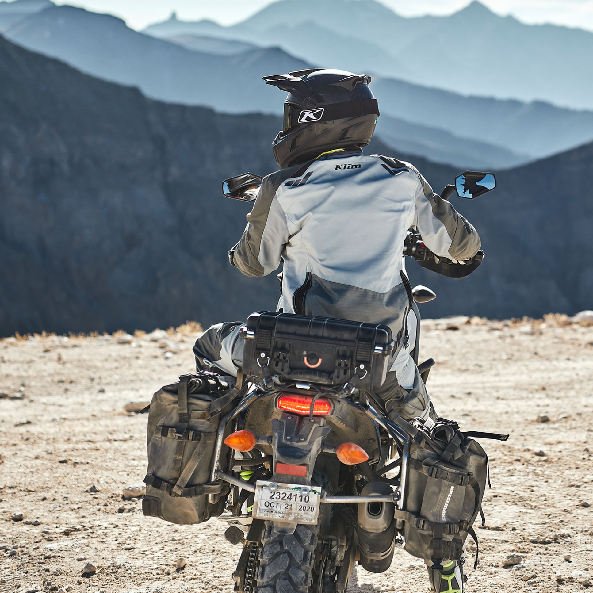 Person riding a motorcycle in a desert landscape with mountains in the background