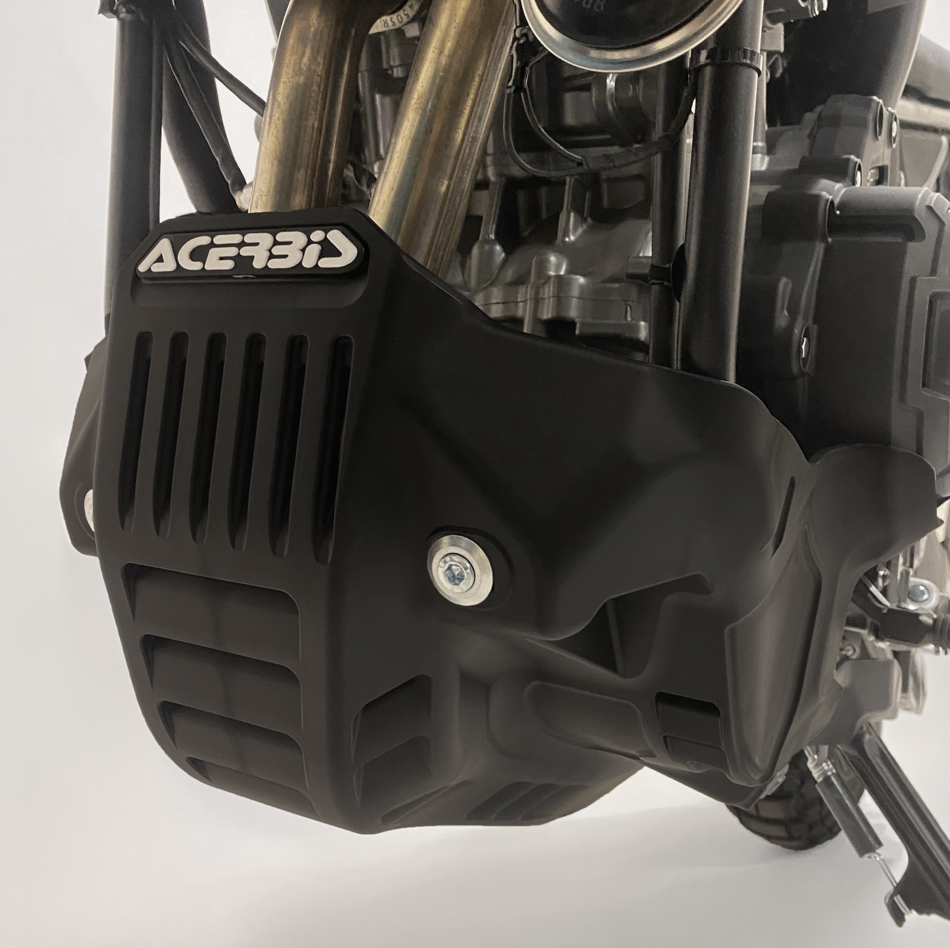 Close-up of a motorcycle engine with Acerbis branding on a white background
