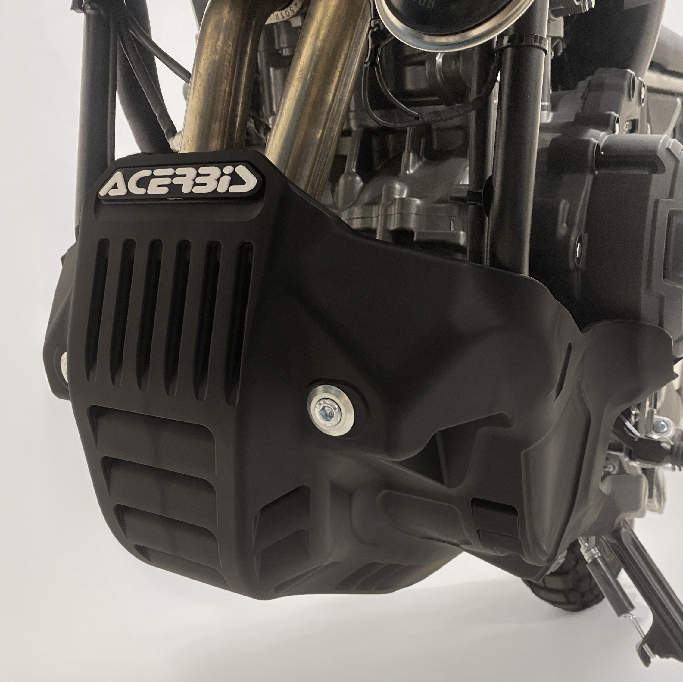 Close-up of a motorcycle engine with Acerbis branding on a white background