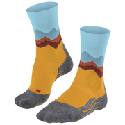 A pair of crew socks with a mountain landscape pattern, featuring a mustard yellow body, gray toe and heel areas, and light blue and brown mountain peaks on the cuff.