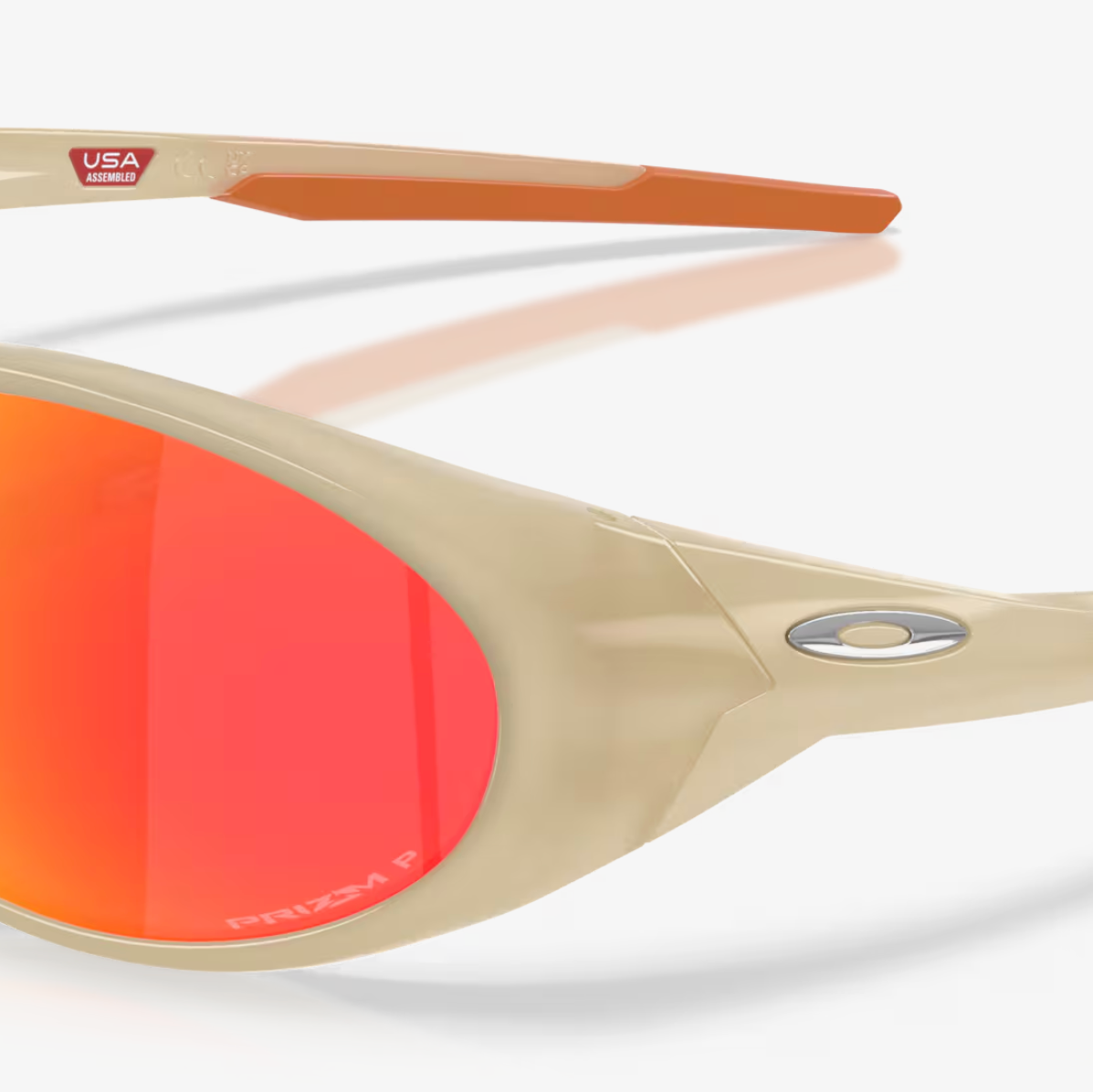 Oakley sunglasses with a translucent beige frame, orange-tipped arms, and vibrant orange-to-yellow mirrored lenses.