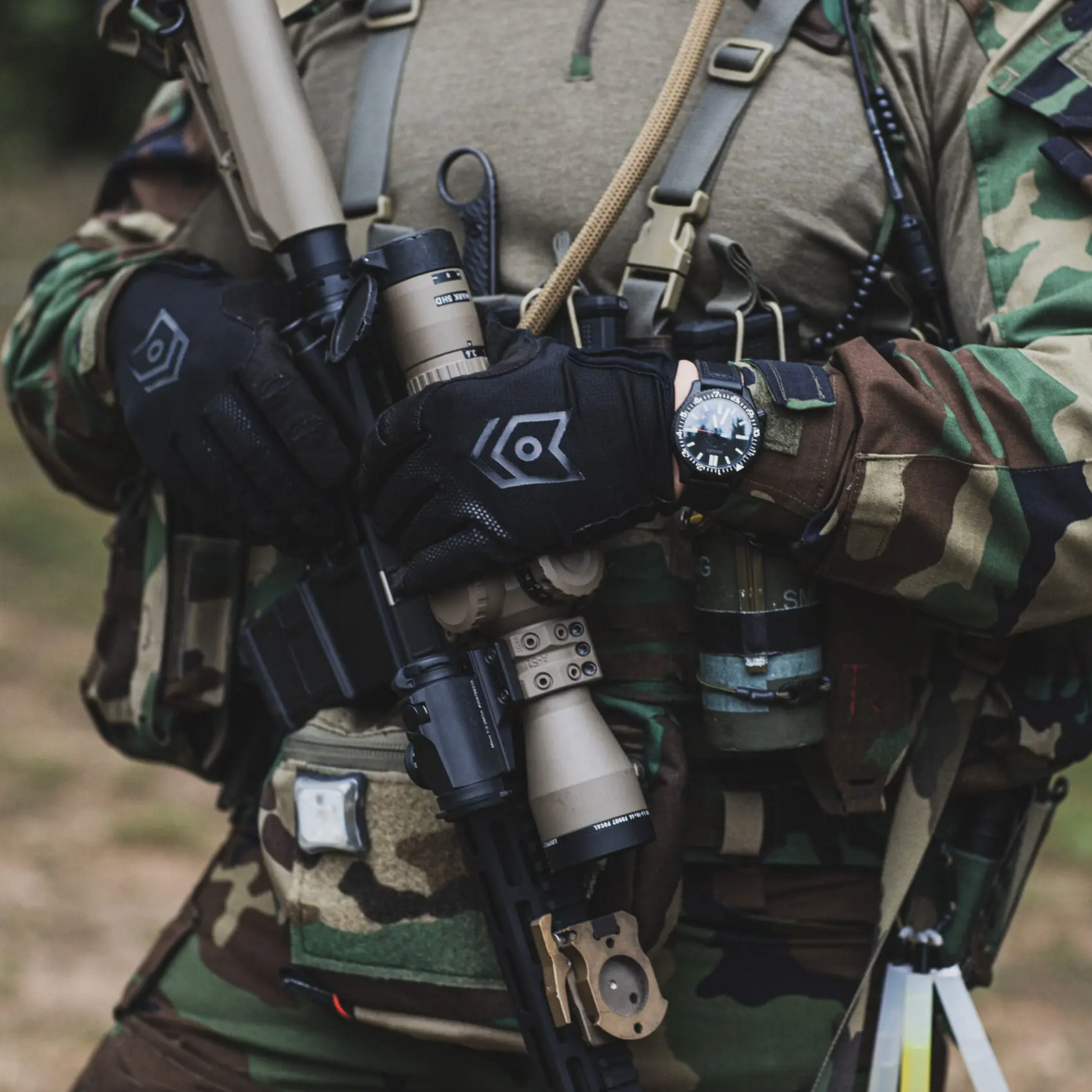 Person in camouflage gear with tactical equipment in a natural setting