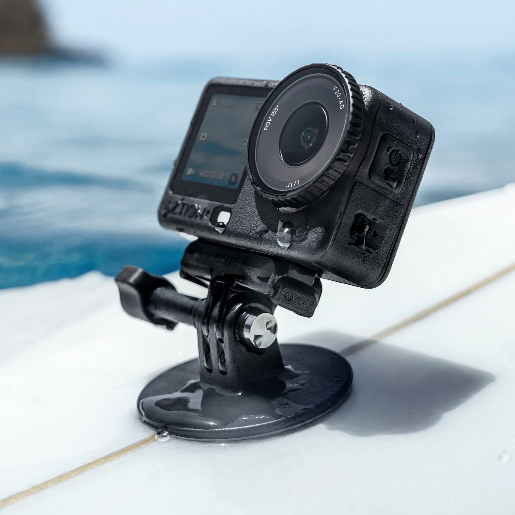 A black action camera mounted on a suction cup stand, set against a blurred background of blue water and a light-colored deck.