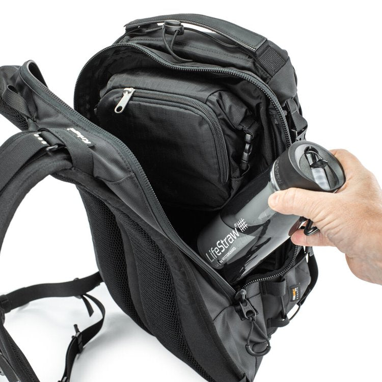 Black backpack with a LifeStraw water bottle being placed inside on a white background