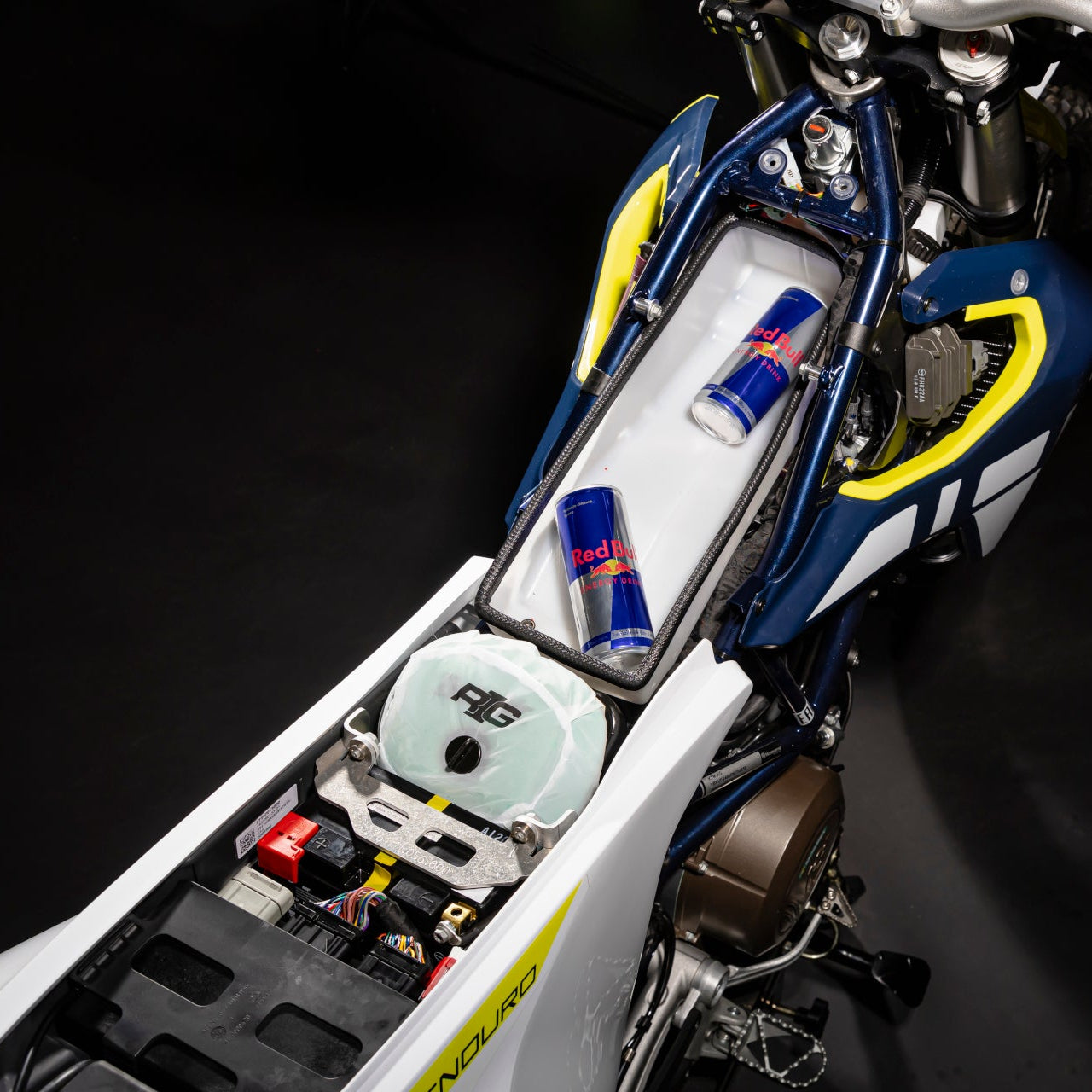 Close-up of a motorcycle's storage compartment with Red Bull energy drinks on a black background