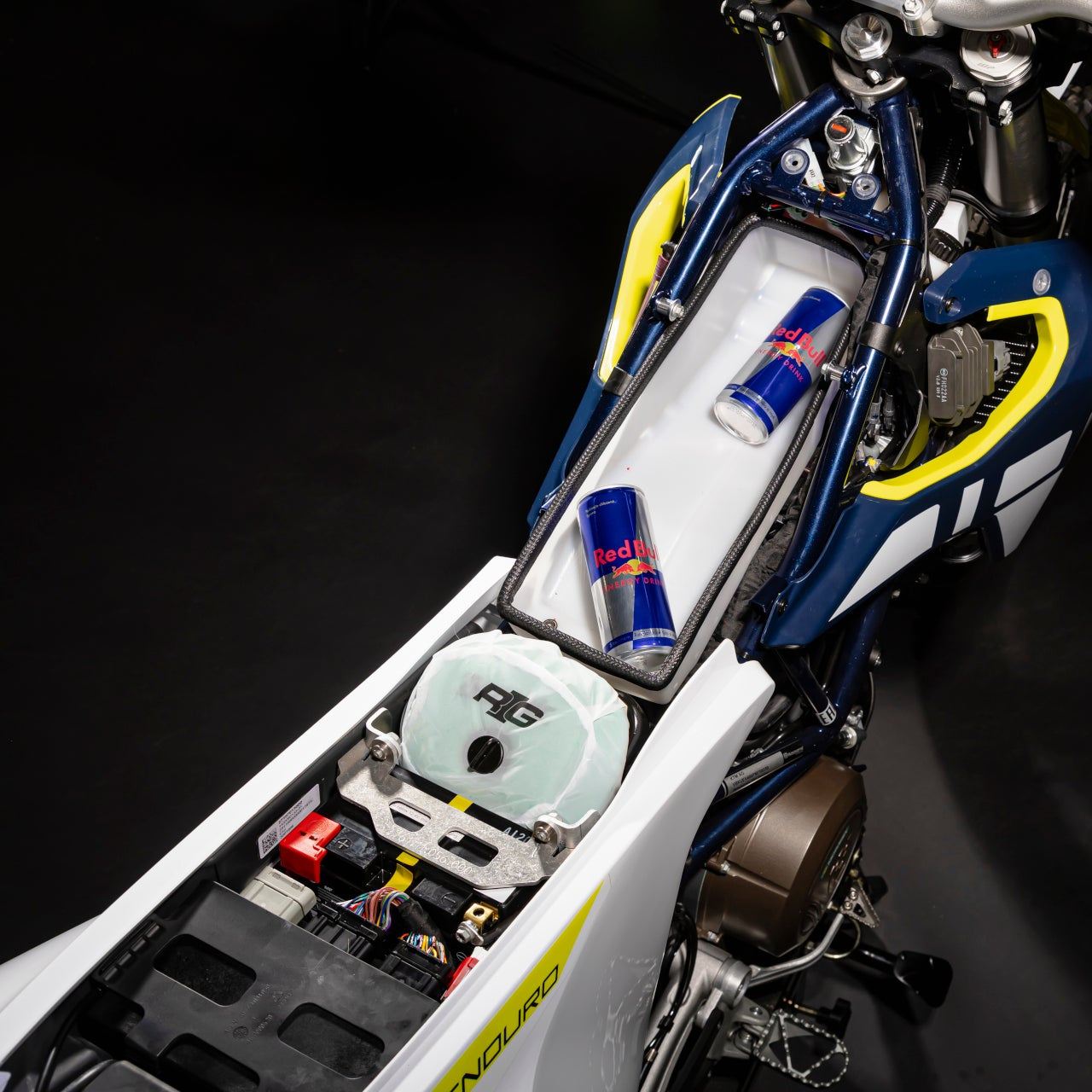 Close-up of a motorcycle's storage compartment with Red Bull energy drinks on a black background